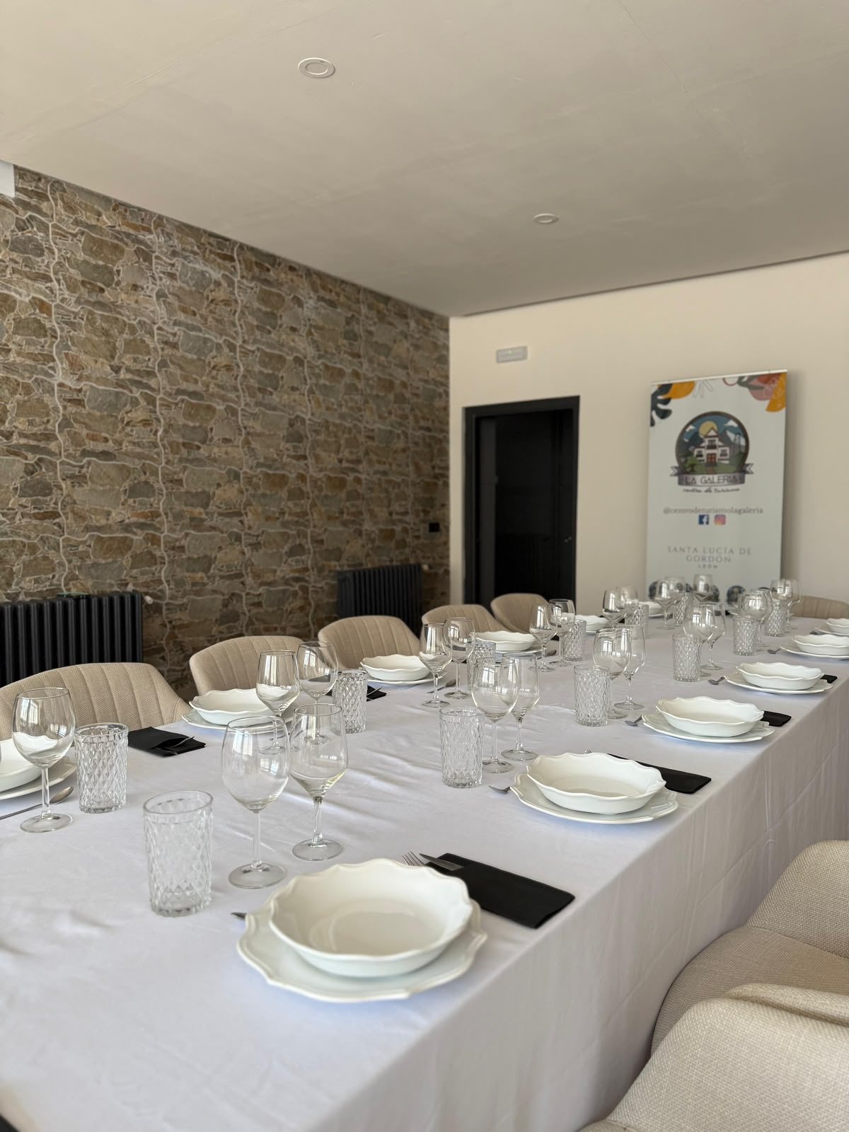 Comedor de La Galería con la mesa puesta y pared de piedra