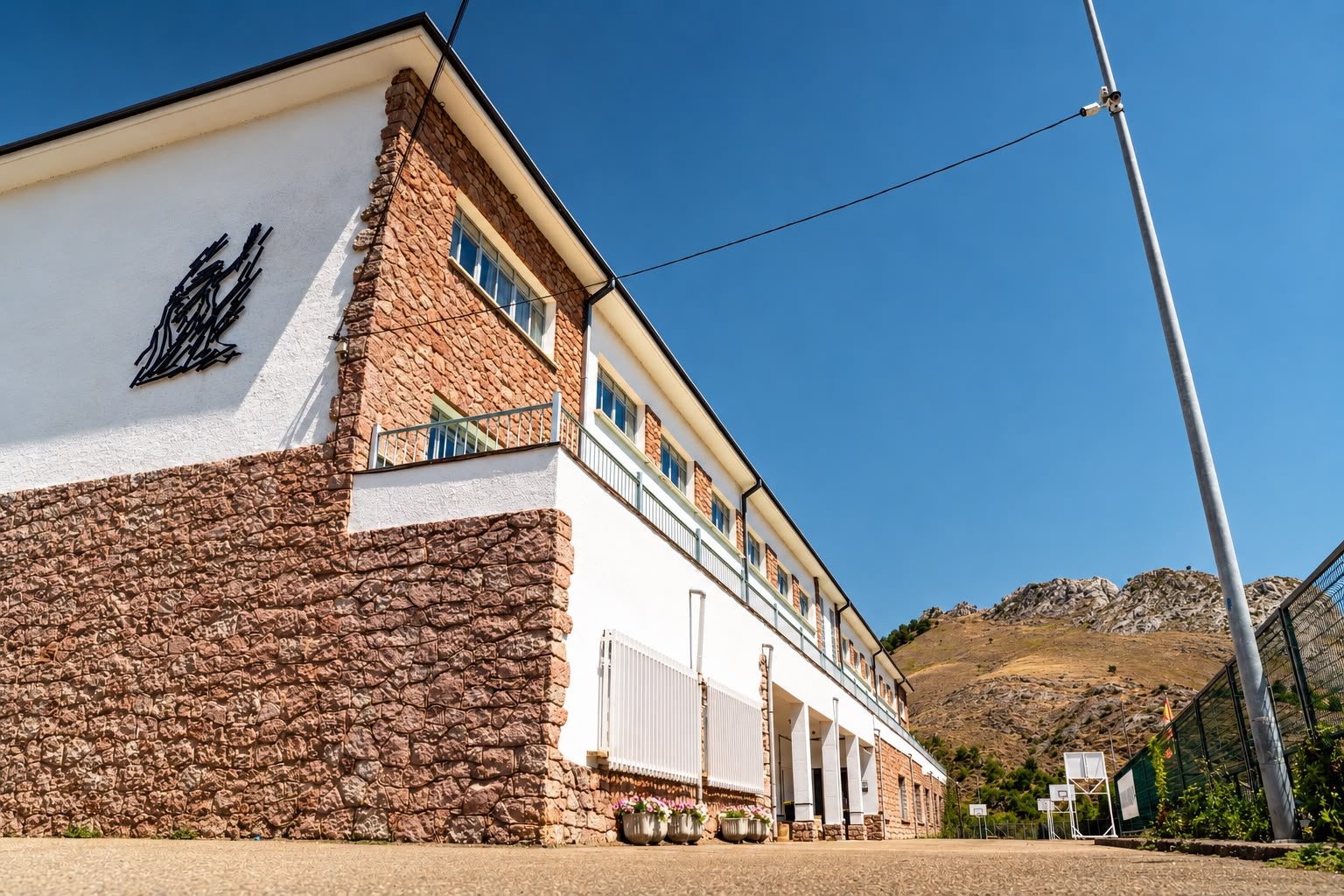 Fachada de piedra del Centro La Galería, el antiguo colegio de Santa Lucía de Gordón, con la montaña detrás
