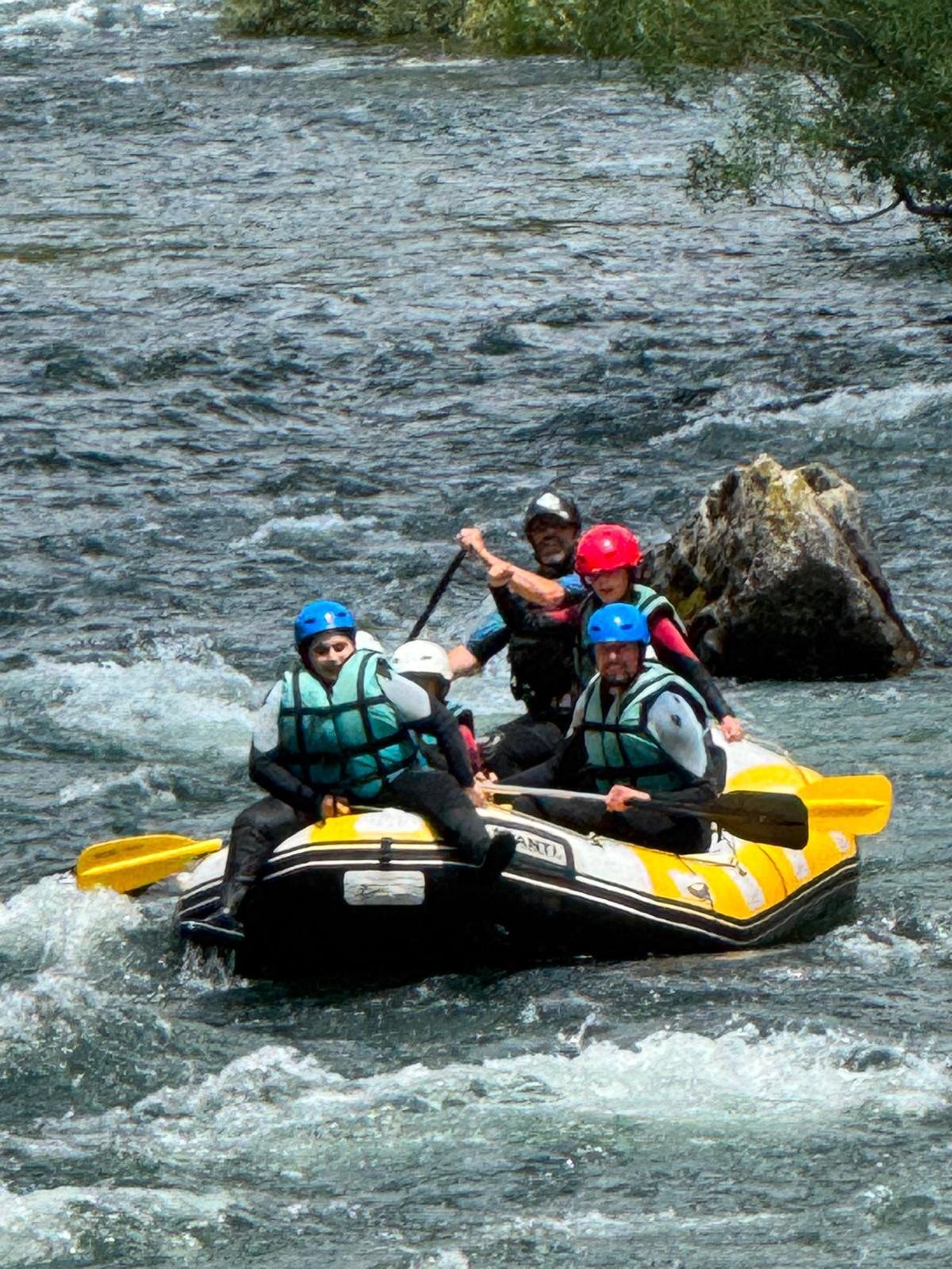 Grupo con cascos y chalecos bajando el río en una balsa de rafting