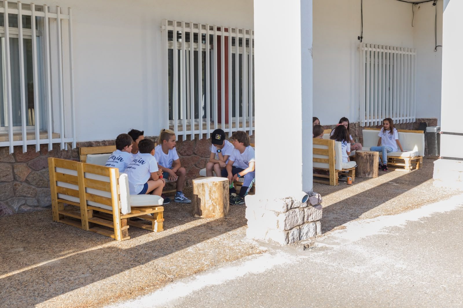 Chicos y chicas charlando en los sofás de palés del porche